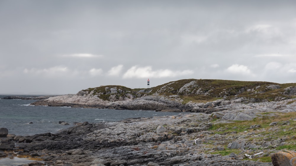 a rocky shore with a lighthouse in the distance