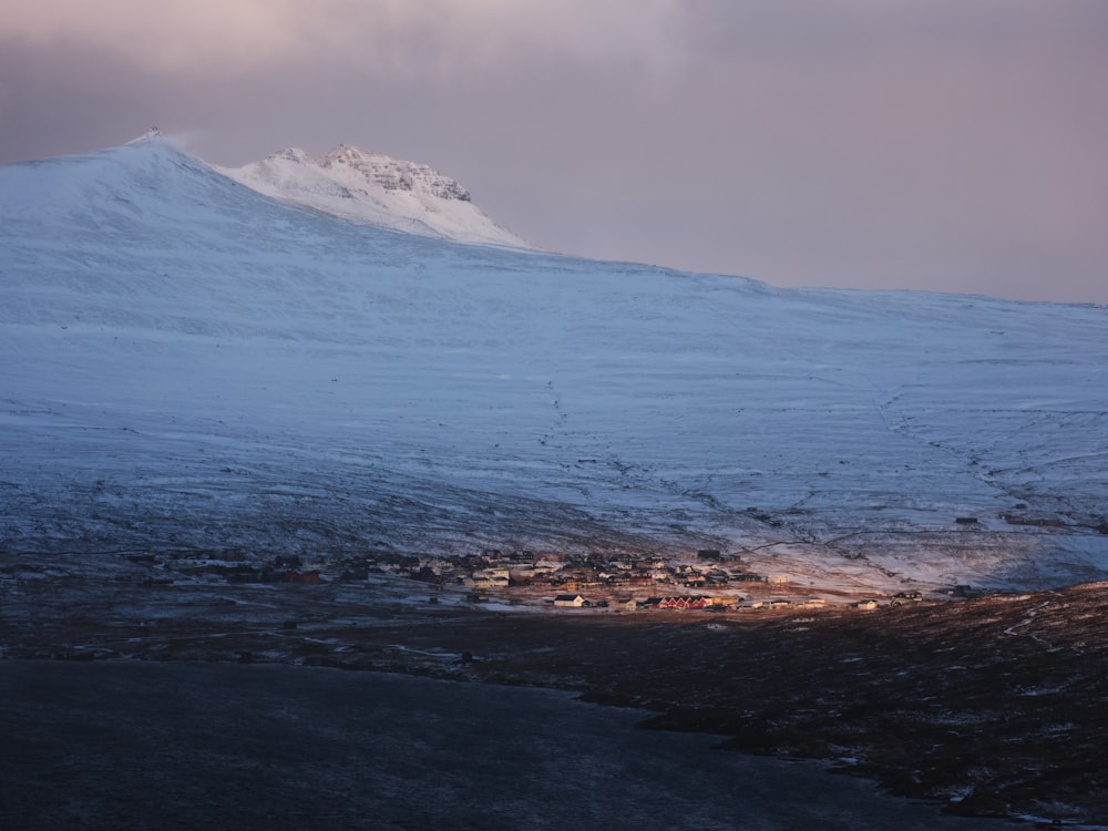 uma montanha coberta de neve com uma pequena aldeia abaixo