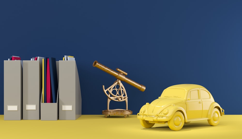 a yellow toy car next to books and a telescope