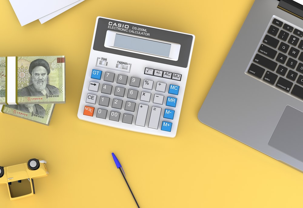 a calculator sitting on top of a desk next to a laptop