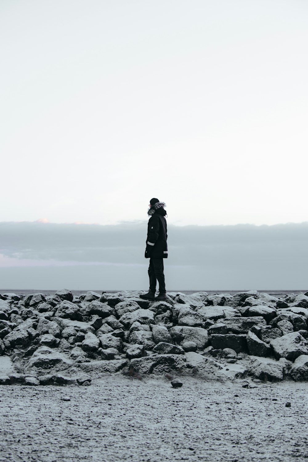 a man standing on a rocky beach next to the ocean