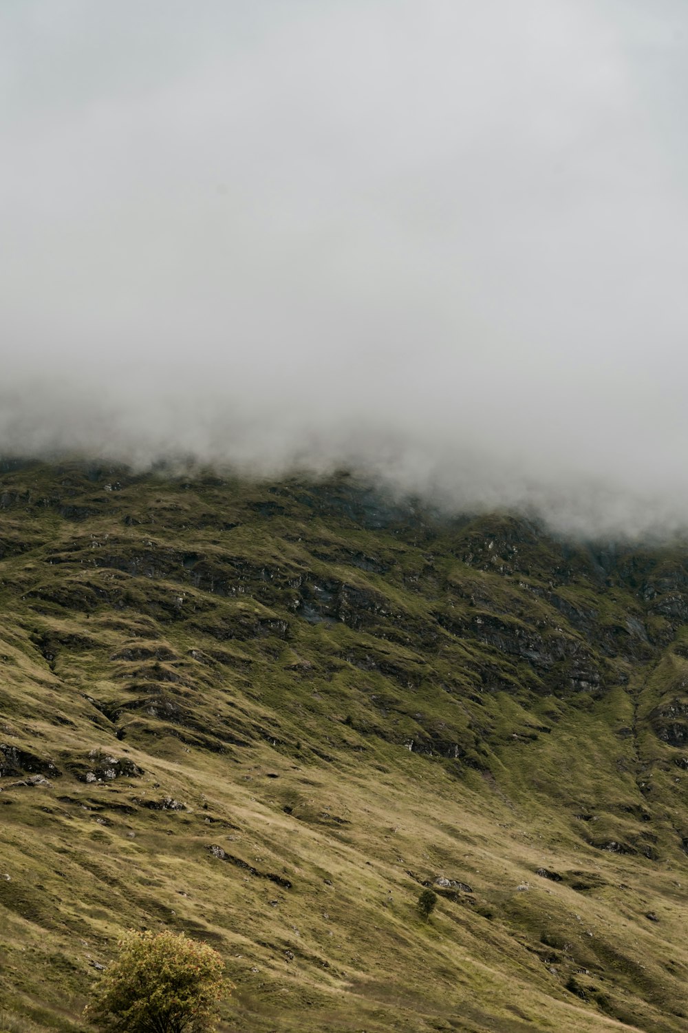 a hill covered in grass and clouds on a cloudy day