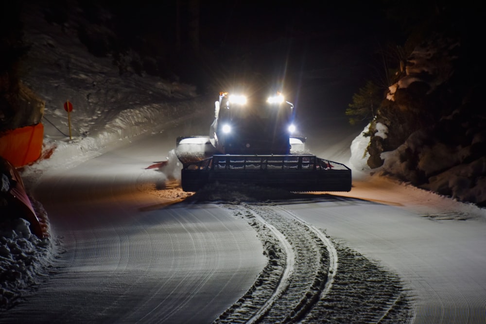 a tractor is driving through the snow at night