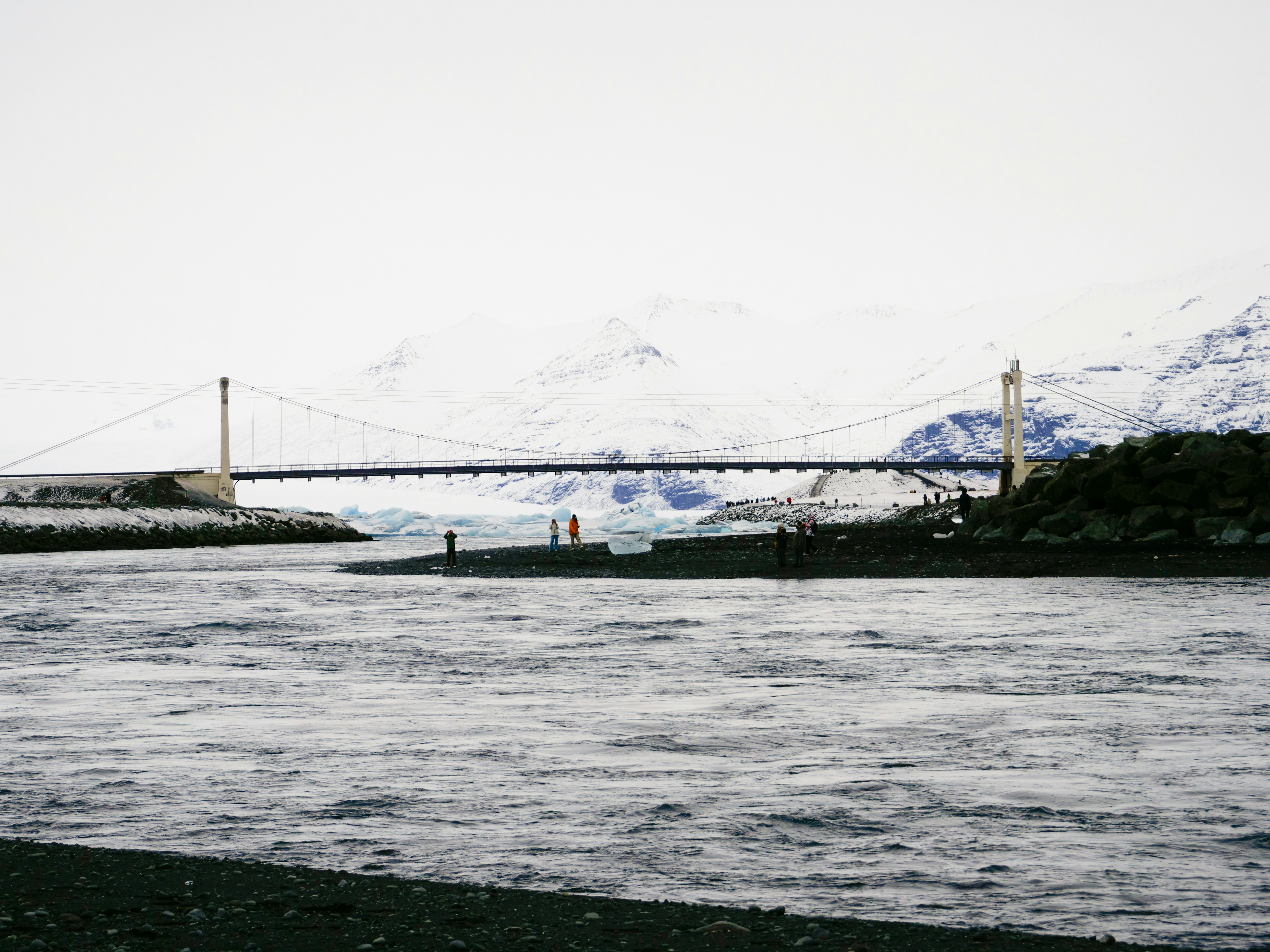 A bridge over a body of water with mountains in the background
