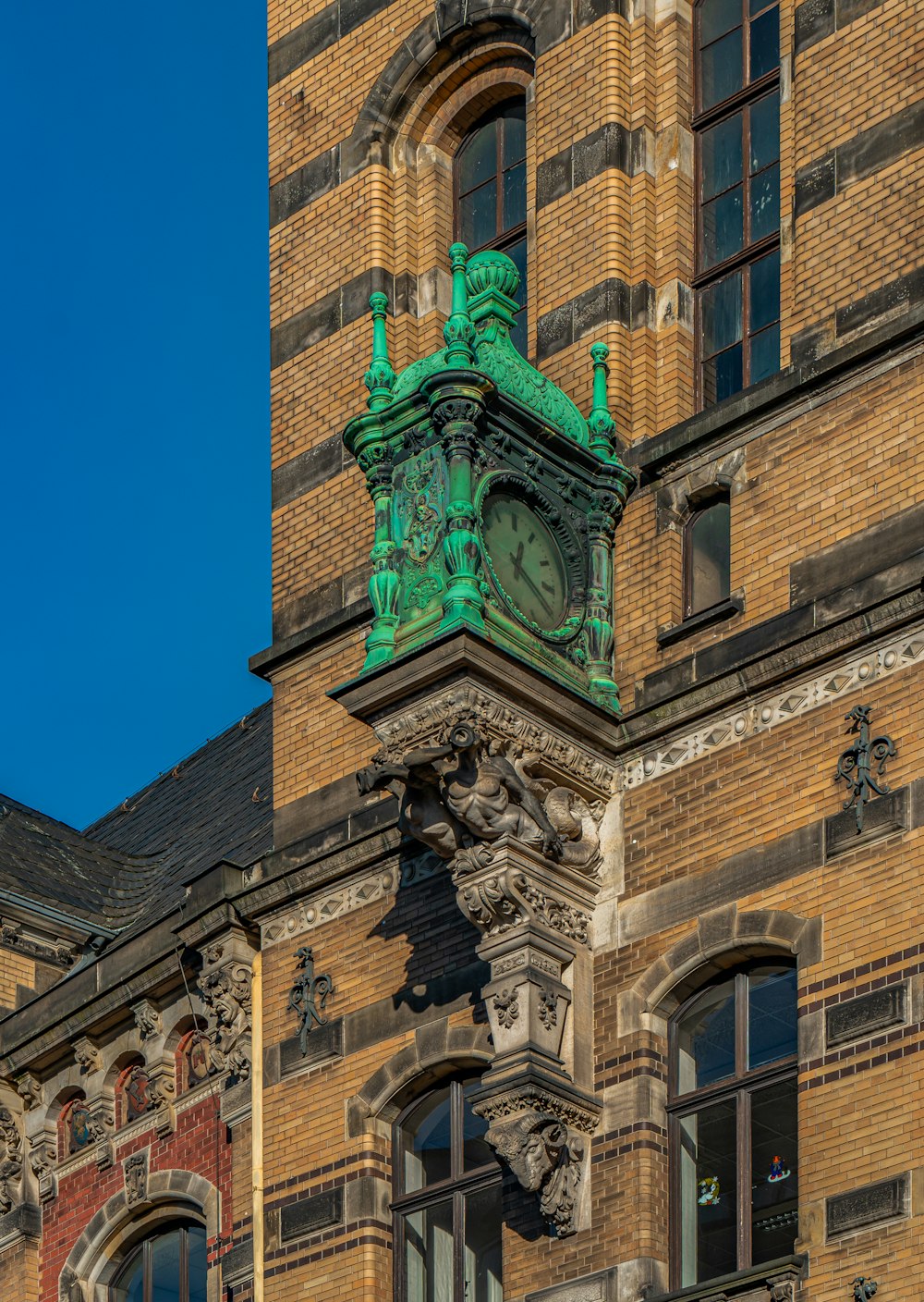 a green clock on the side of a brick building