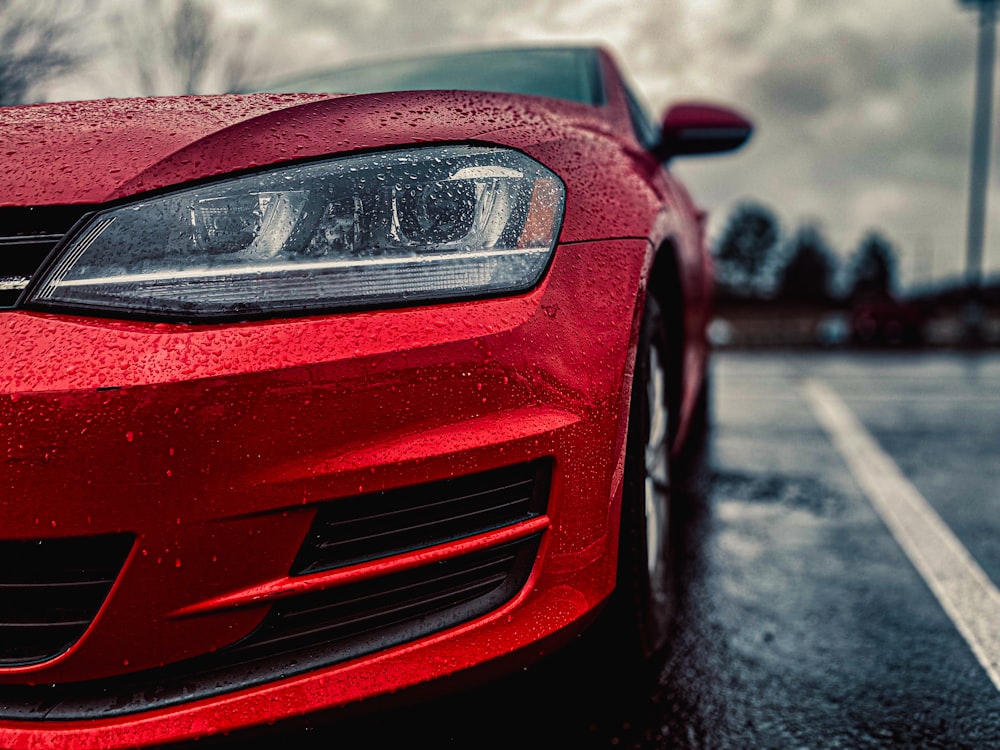 a red car parked on the side of the road in the rain