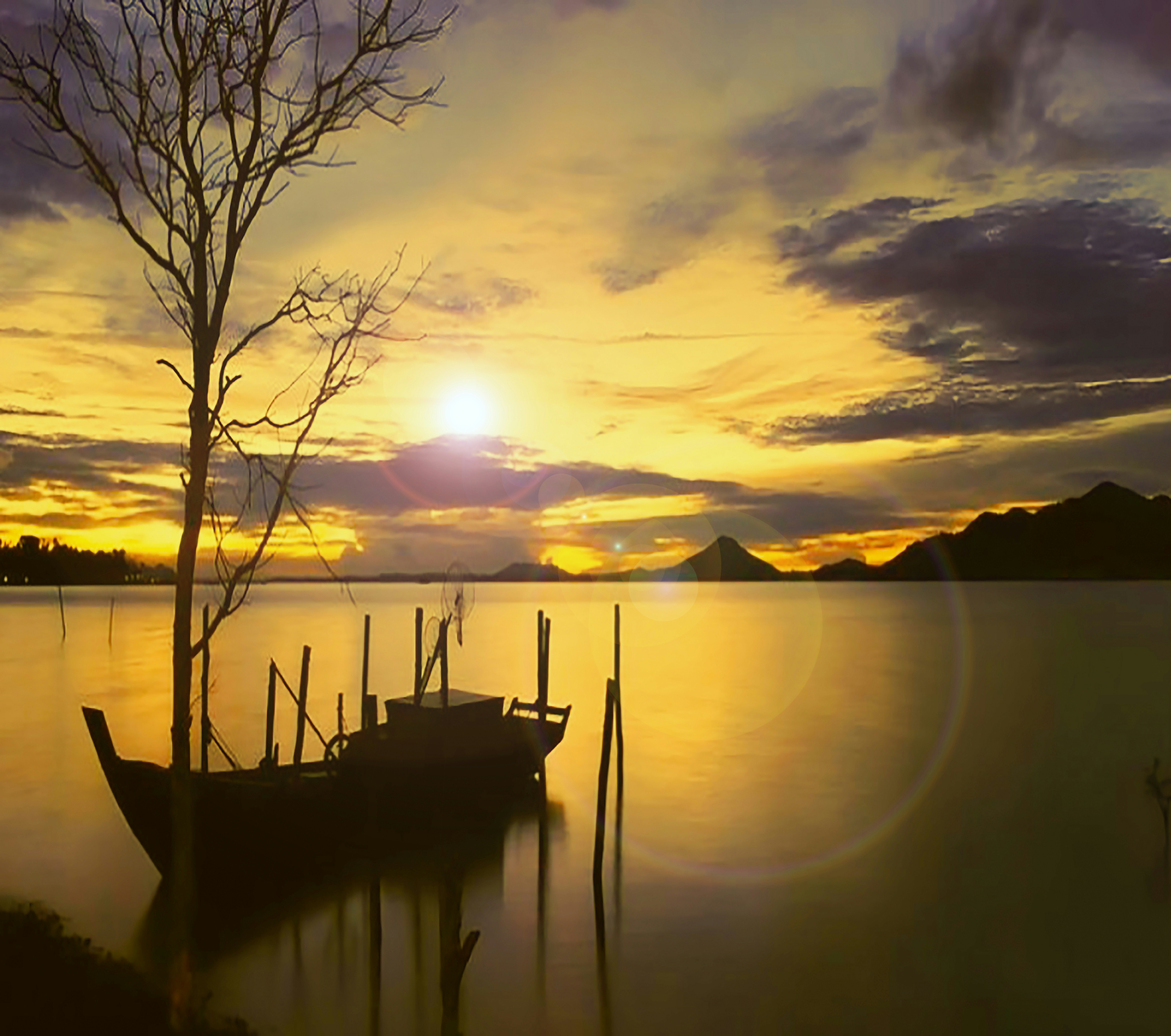 a boat sitting on top of a lake under a cloudy sky
