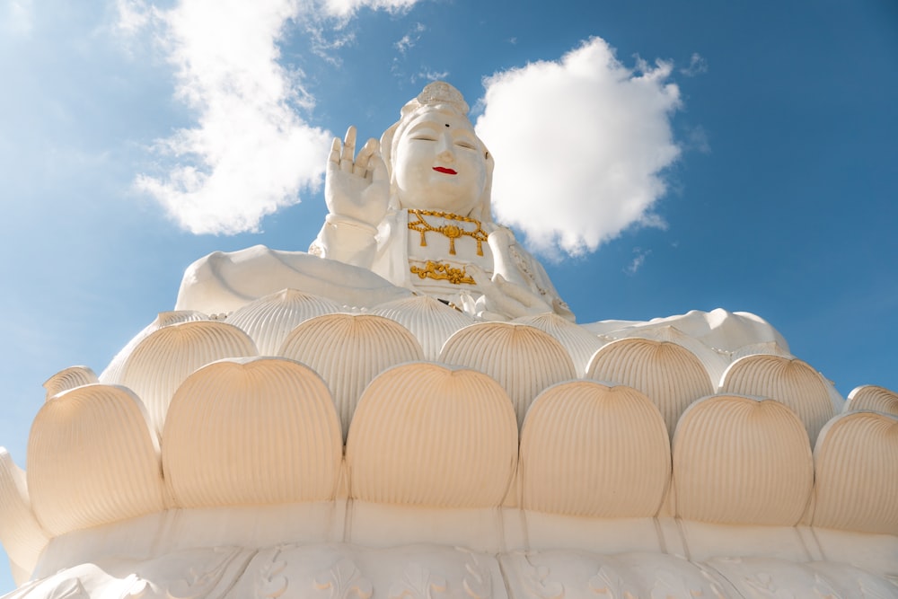 a large white buddha statue sitting on top of a white building