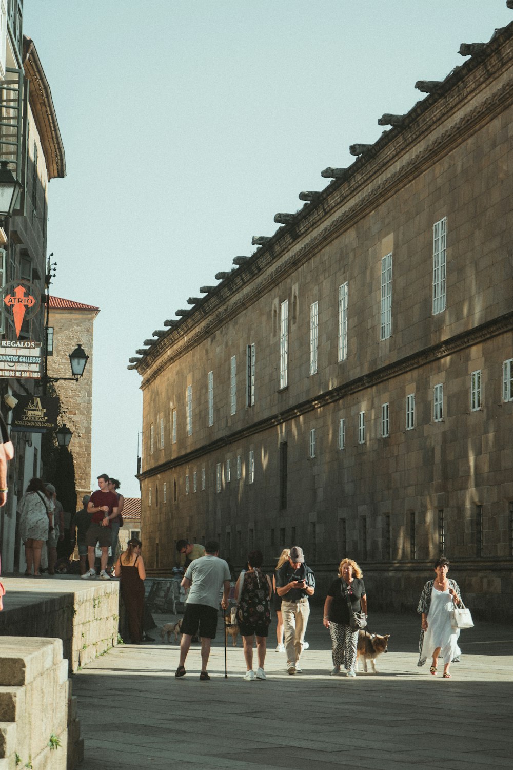 a group of people walking down a street next to tall buildings