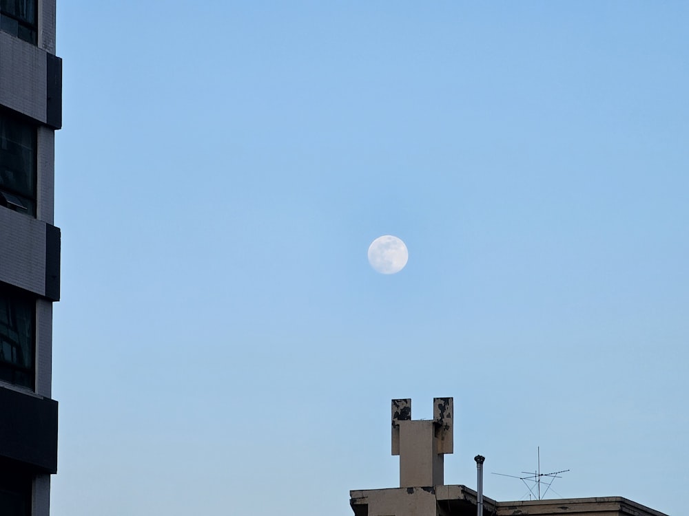 a full moon is seen in the sky above a building