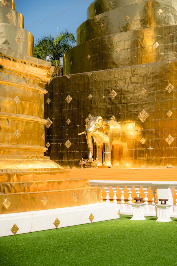 a golden elephant statue sitting on top of a lush green field