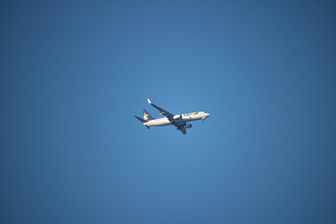 a large jetliner flying through a blue sky, Skymark B737 aircraft photographed from the Shibuya crossing