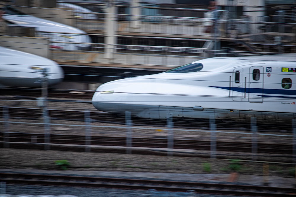 two bullet trains sitting on the tracks next to each other