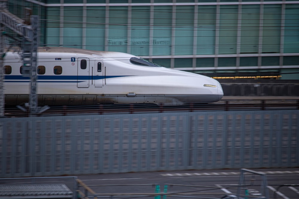 a white and blue train traveling past a tall building