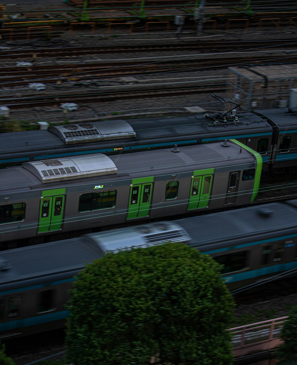 a green and silver train traveling down train tracks