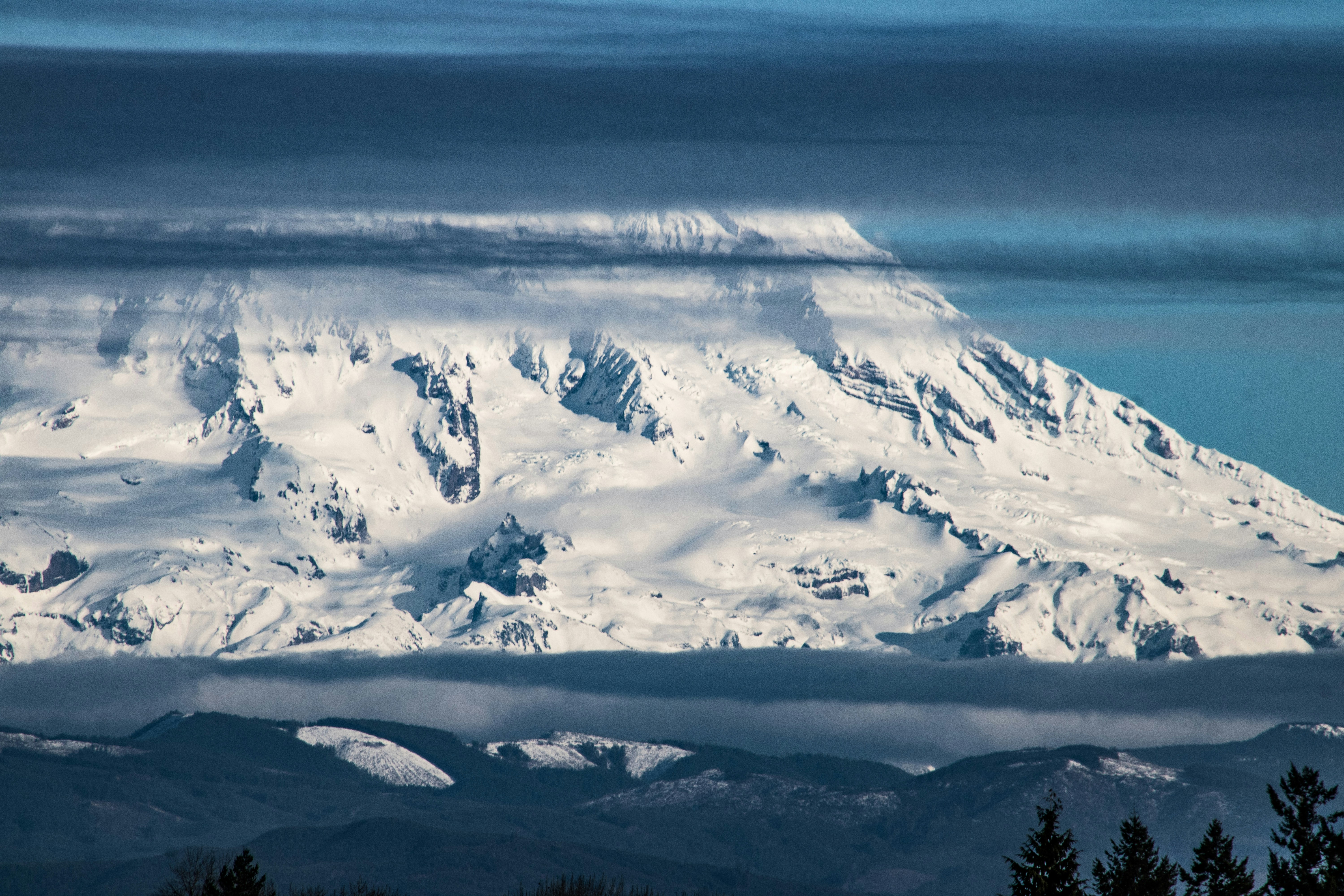 a large mountain covered in snow under a cloudy sky