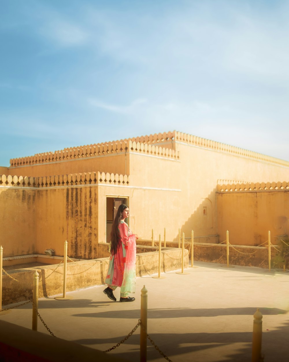 a woman in a pink dress walking in front of a building