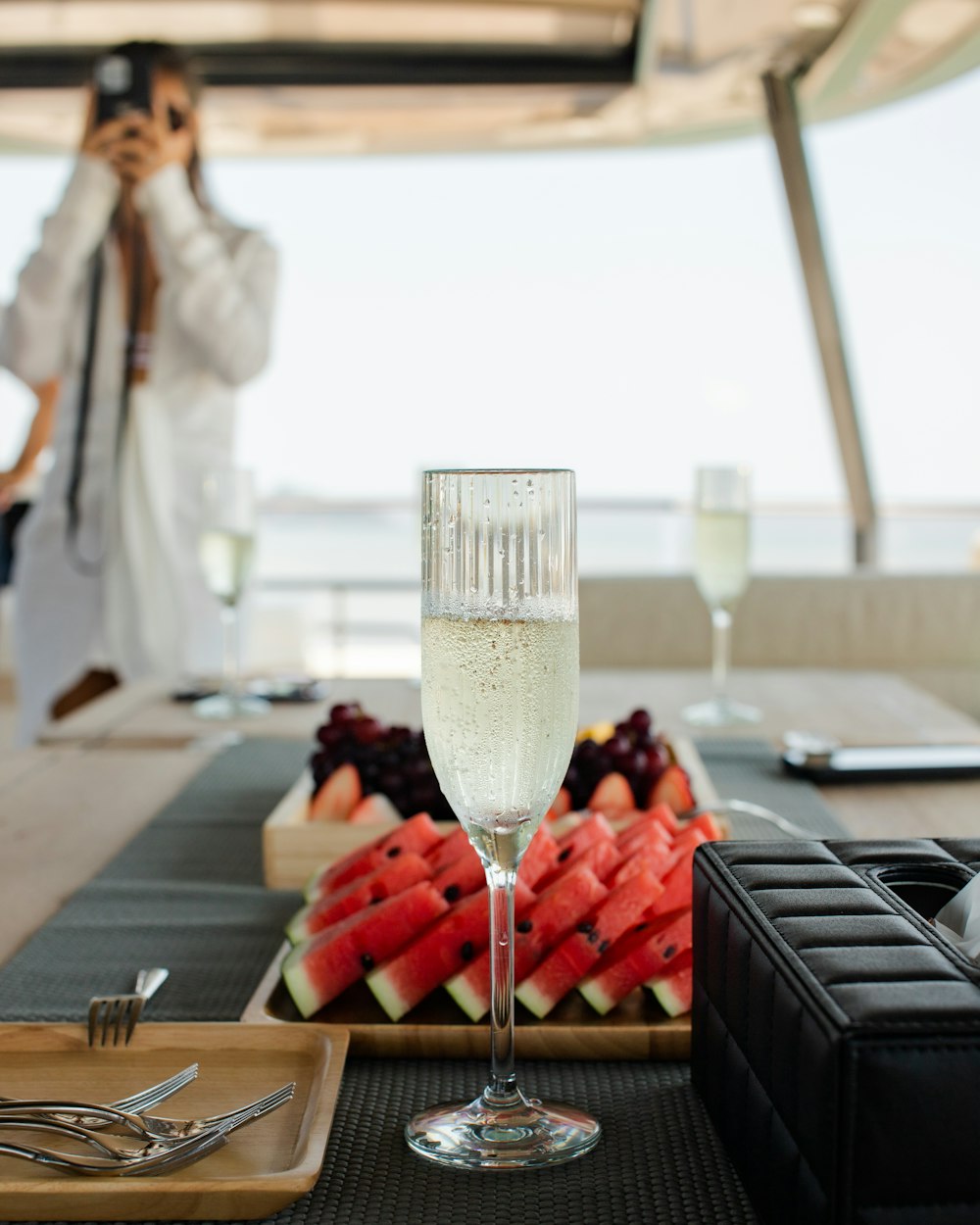 a woman taking a picture of watermelon slices and a glass of wine