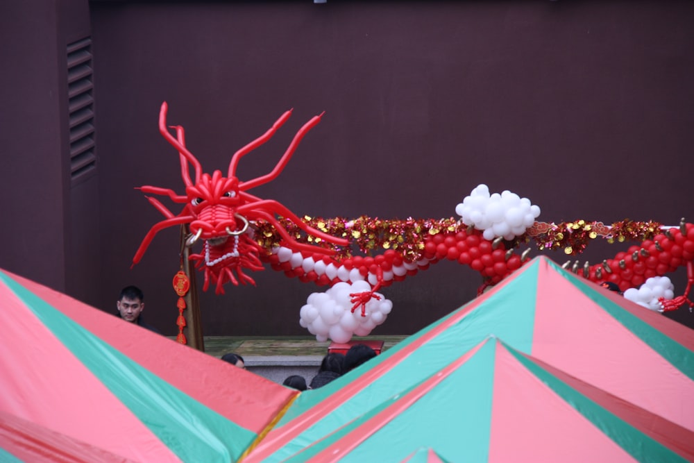 a red dragon statue sitting on top of a green and pink tent