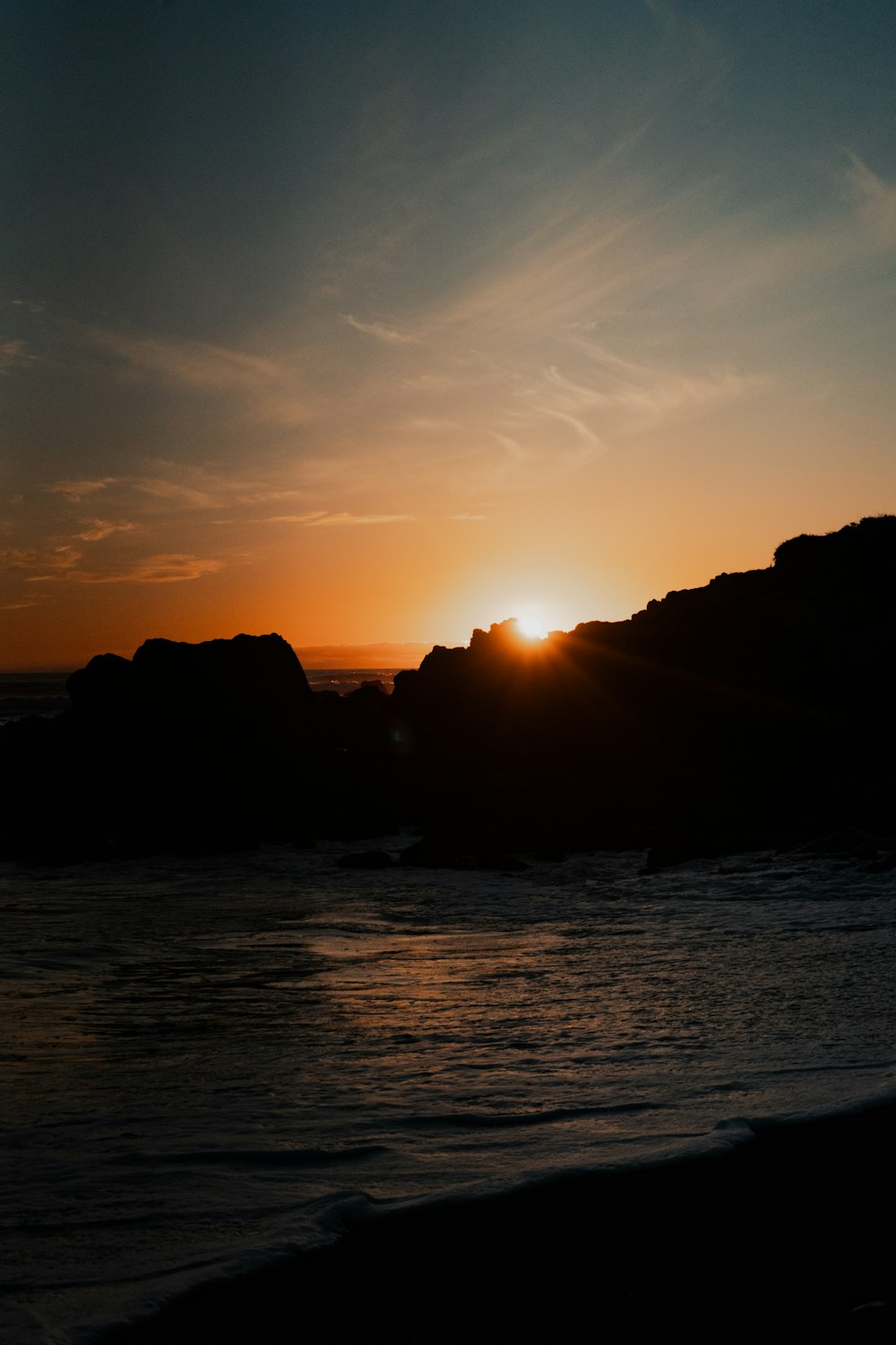 Die Sonne geht über dem Meer und den Felsen unter