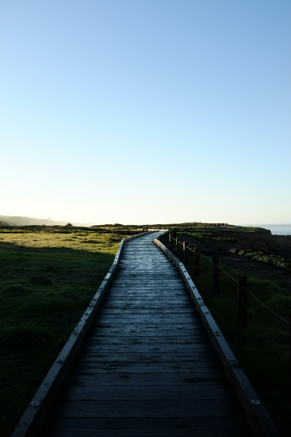 a wooden walkway leading to a grassy field