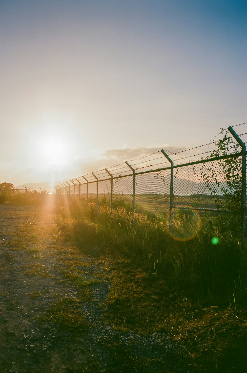 the sun is setting behind a barbed wire fence