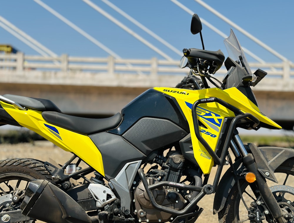 a yellow and black motorcycle parked in front of a bridge