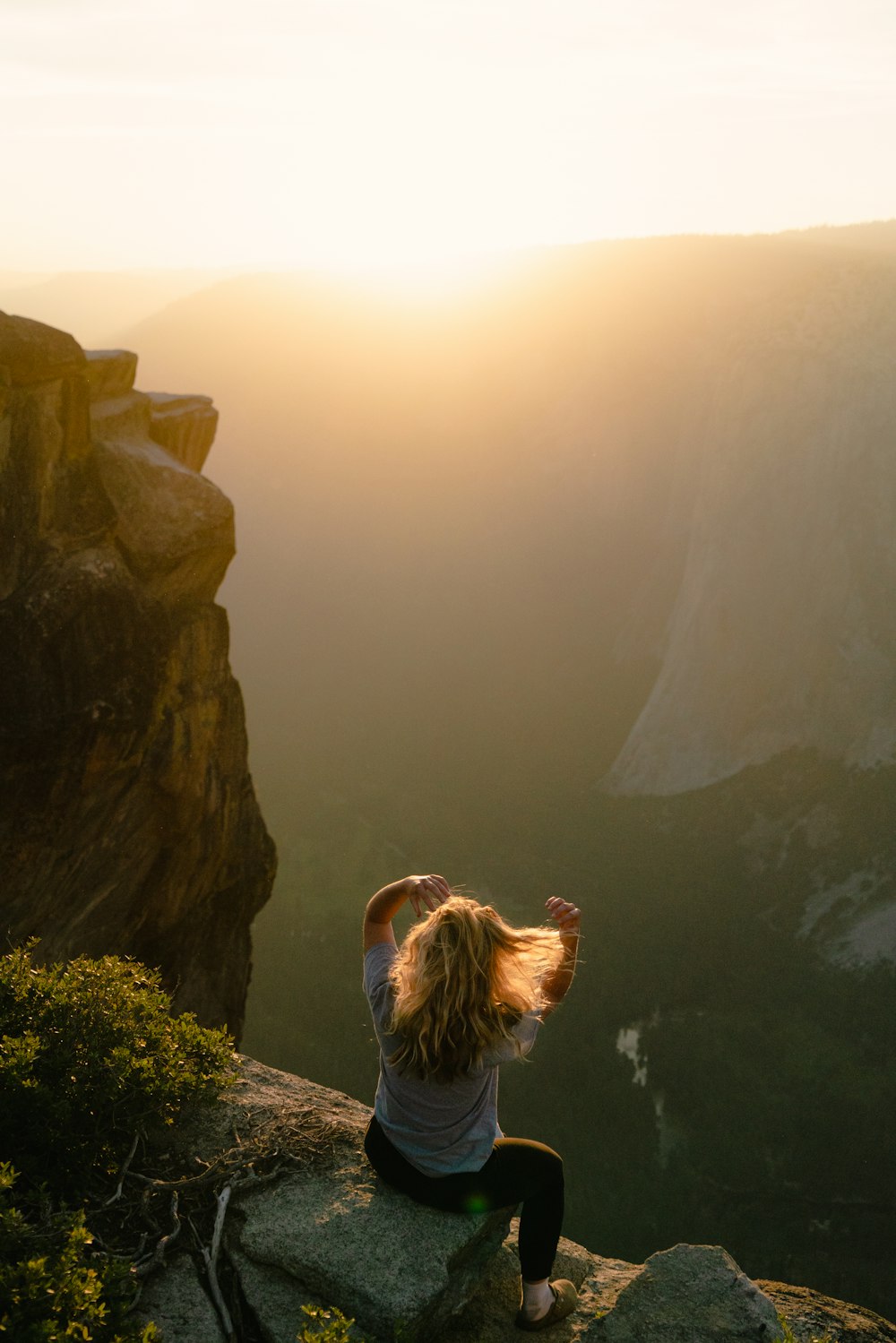 渓谷を見下ろす崖の上に座る女性