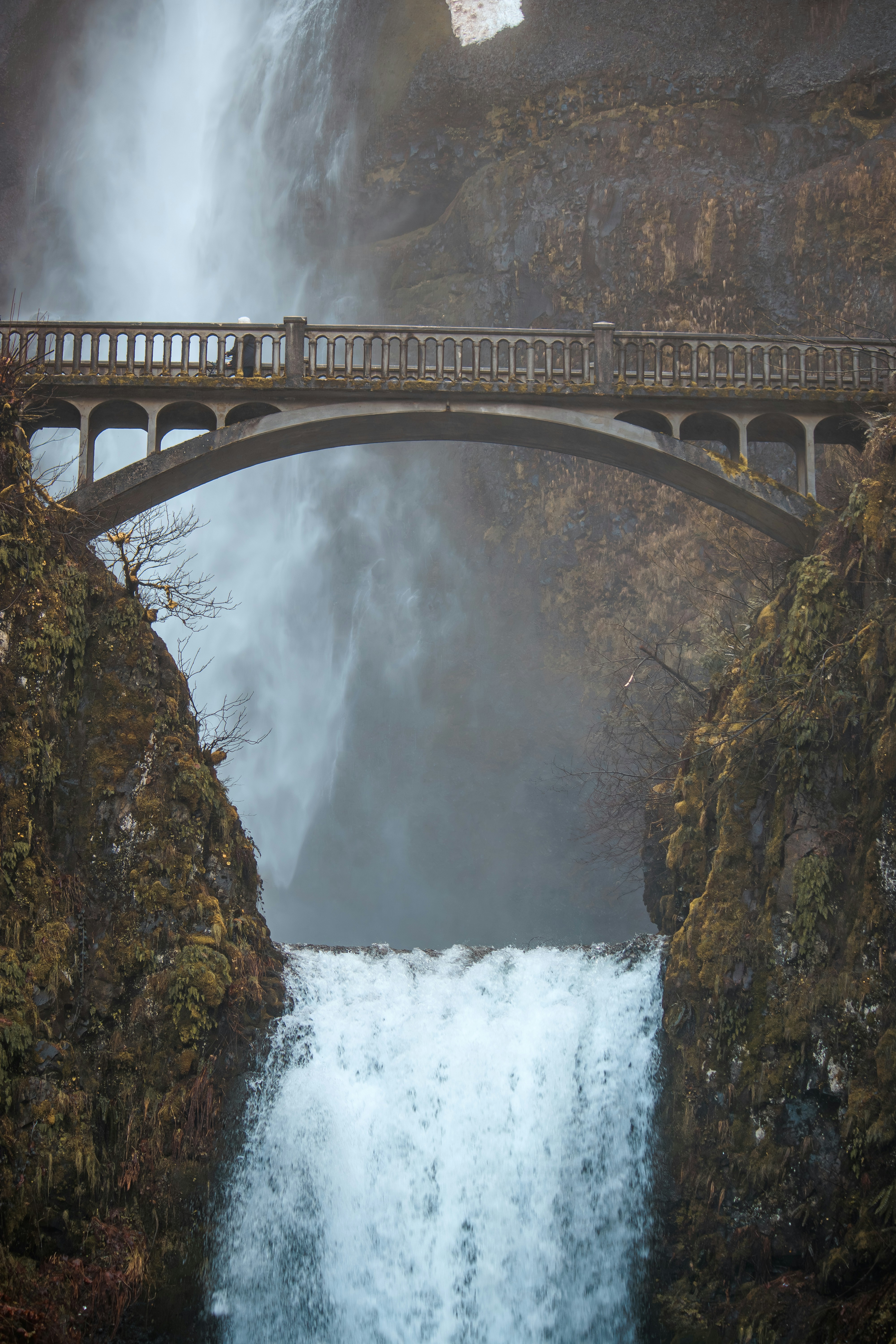 un ponte su uno specchio d'acqua con una cascata sullo sfondo