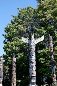 a group of totem poles in front of a tree