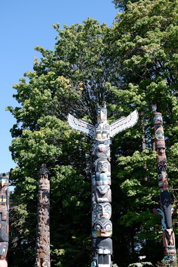 a group of totem poles in front of a tree