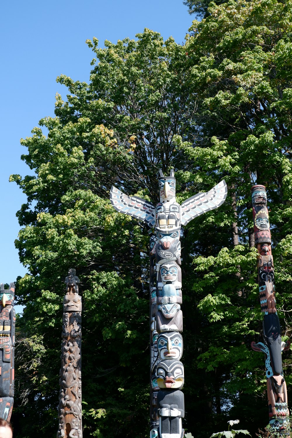 a group of totem poles in front of a tree