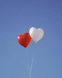 two heart shaped balloons floating in the air