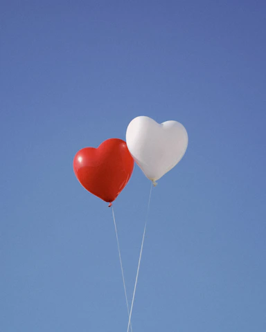 two heart shaped balloons floating in the air