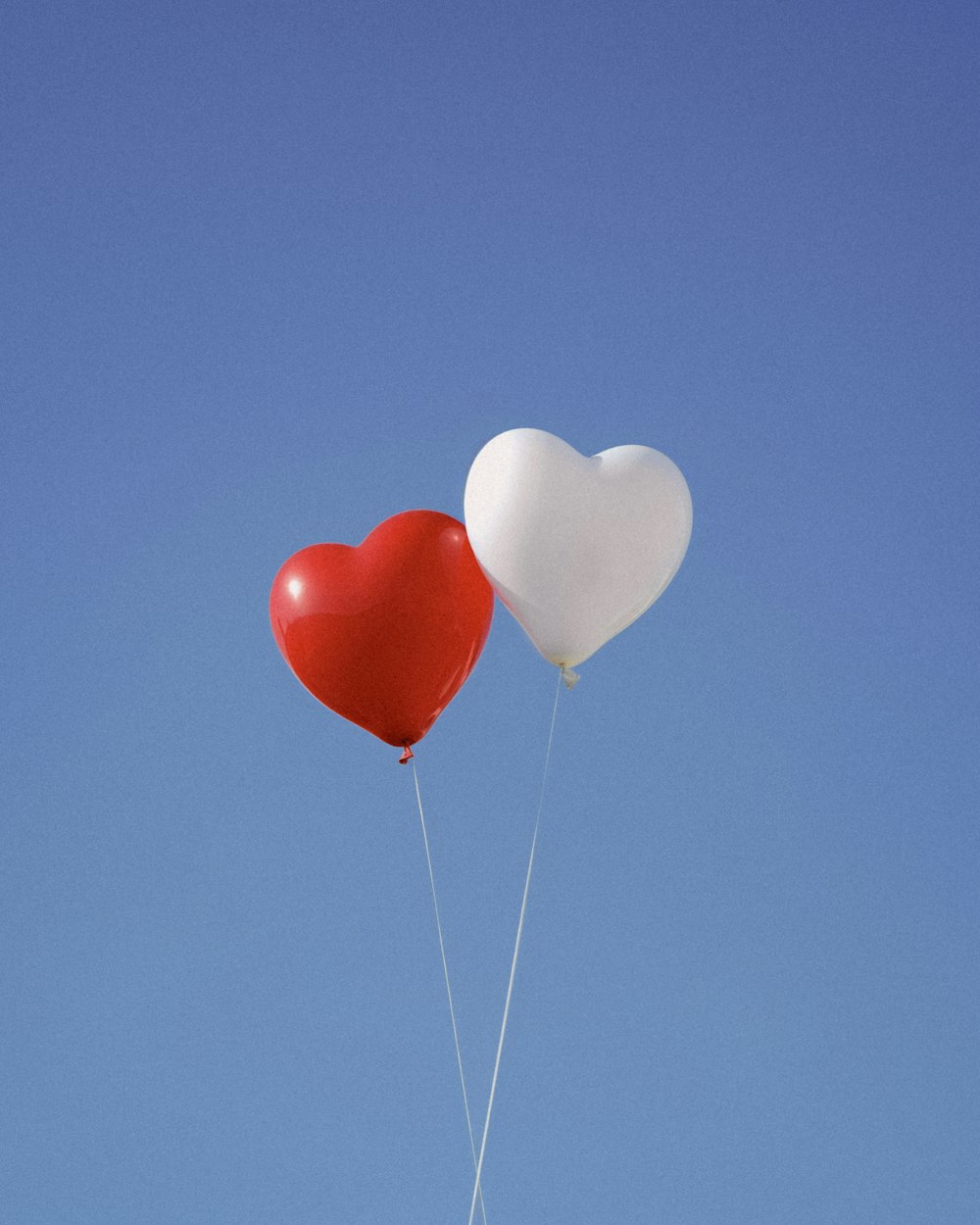 two heart shaped balloons floating in the air