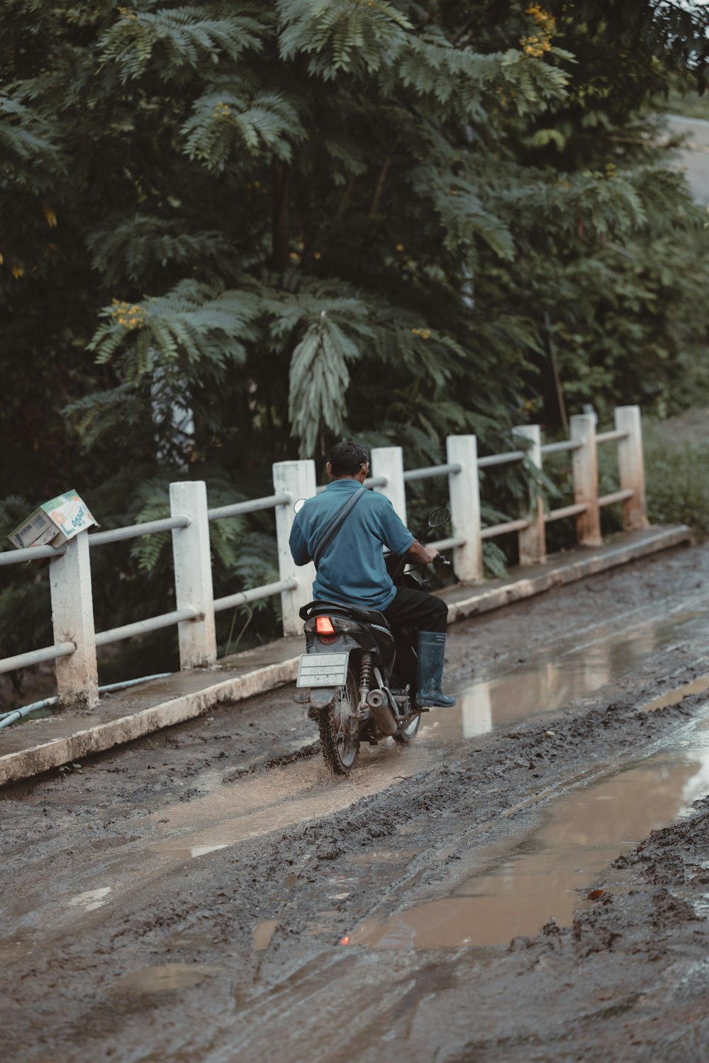 a man riding a motorcycle down a muddy road