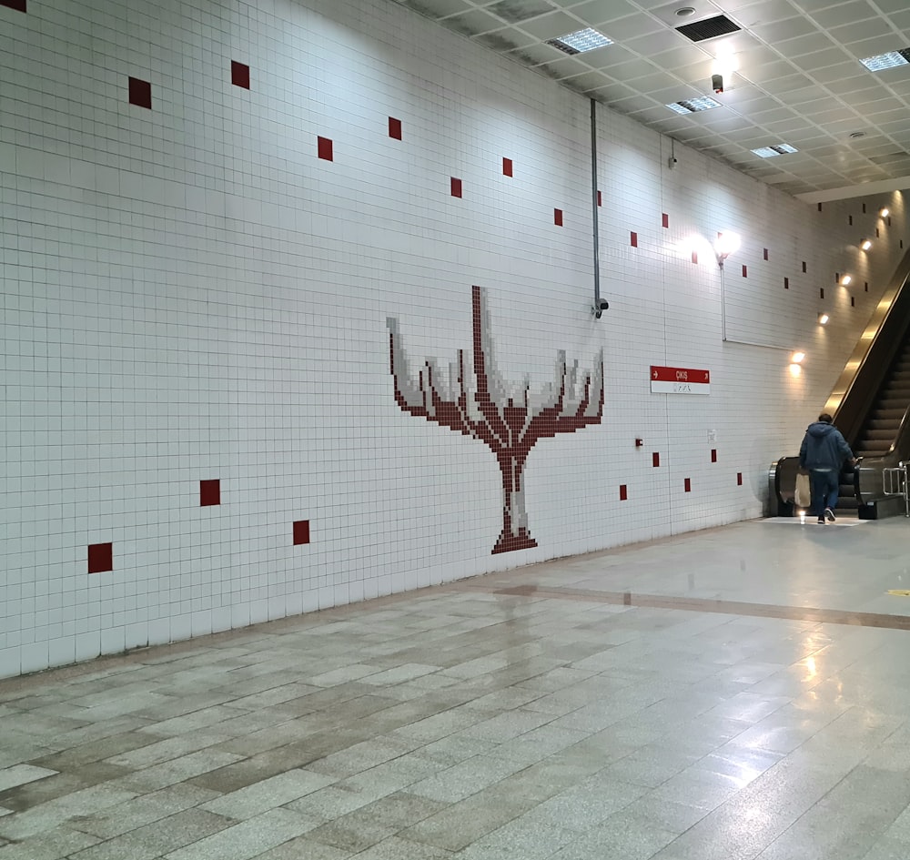 a man standing in a hallway next to a white tiled wall