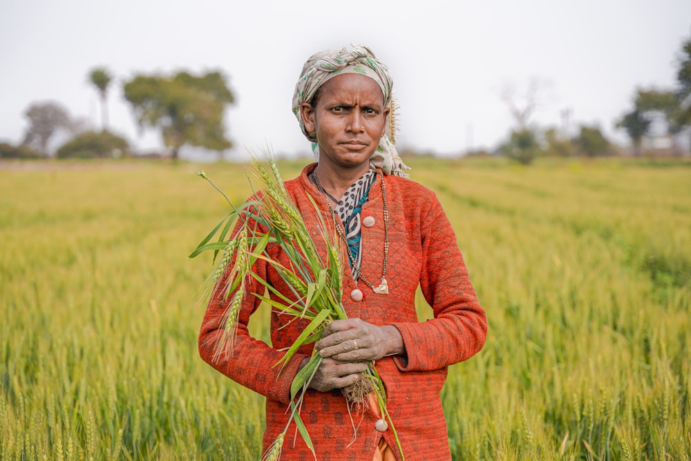 una donna in piedi in un campo con in mano una pianta