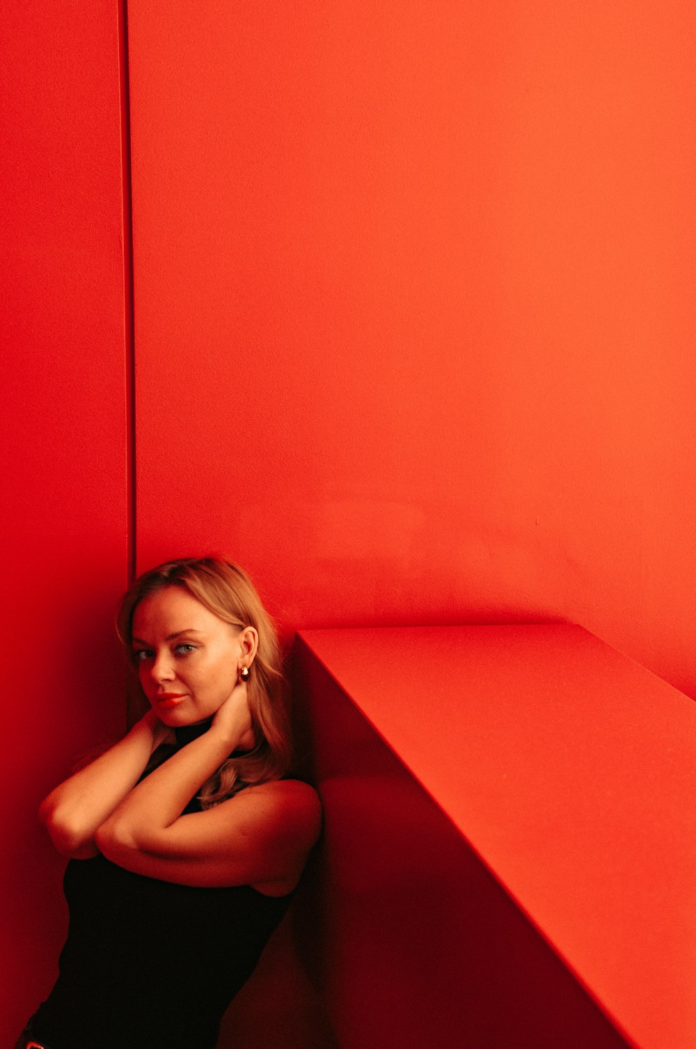 a woman leaning against a red wall in a room