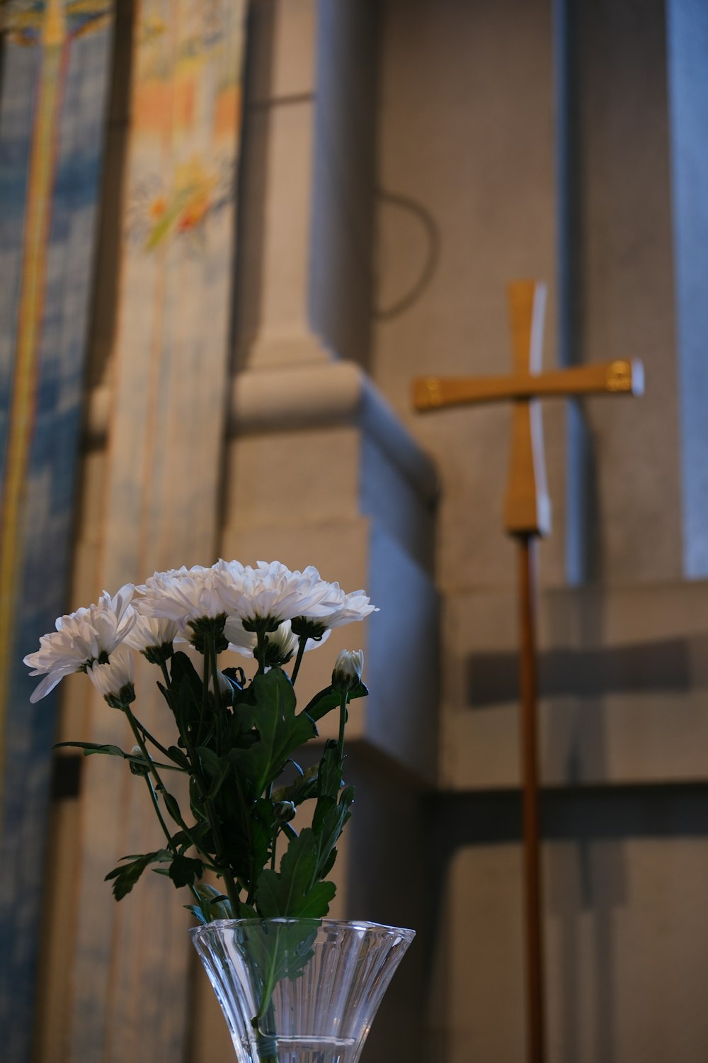 a vase filled with white flowers next to a cross