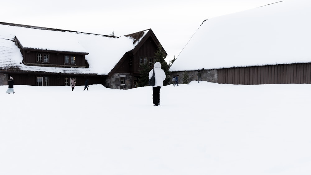 a person standing in the snow in front of a house