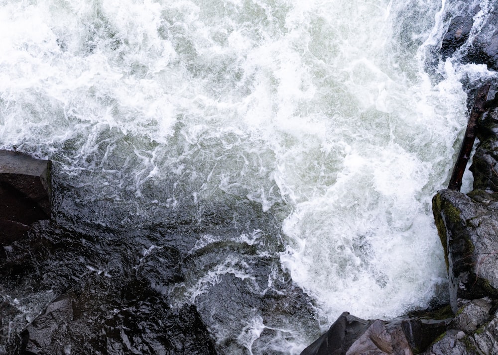 a man standing on a rock next to a body of water