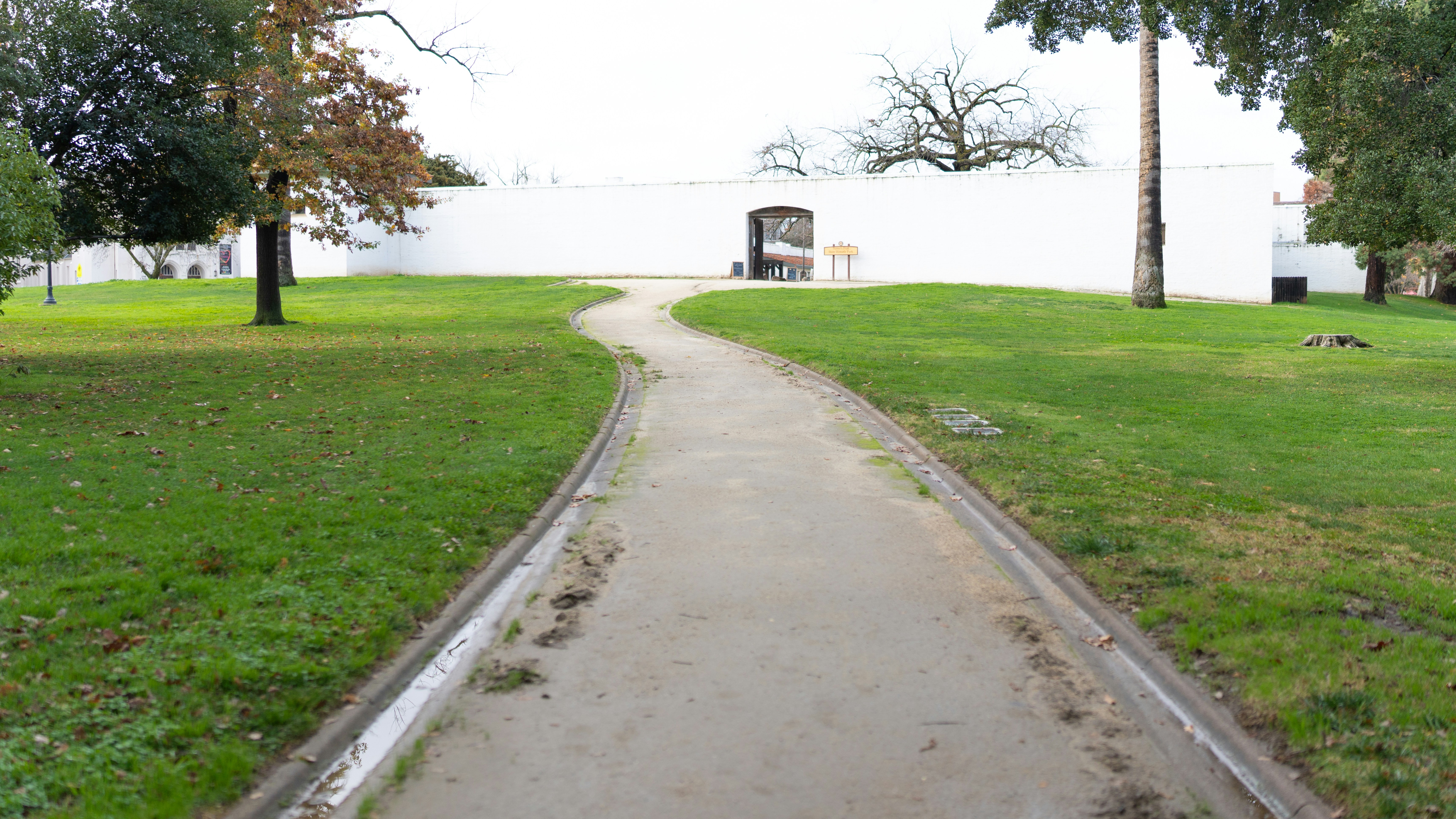 a path in a park with a white building in the background