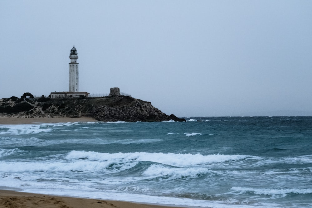 a light house sitting on top of a beach next to the ocean