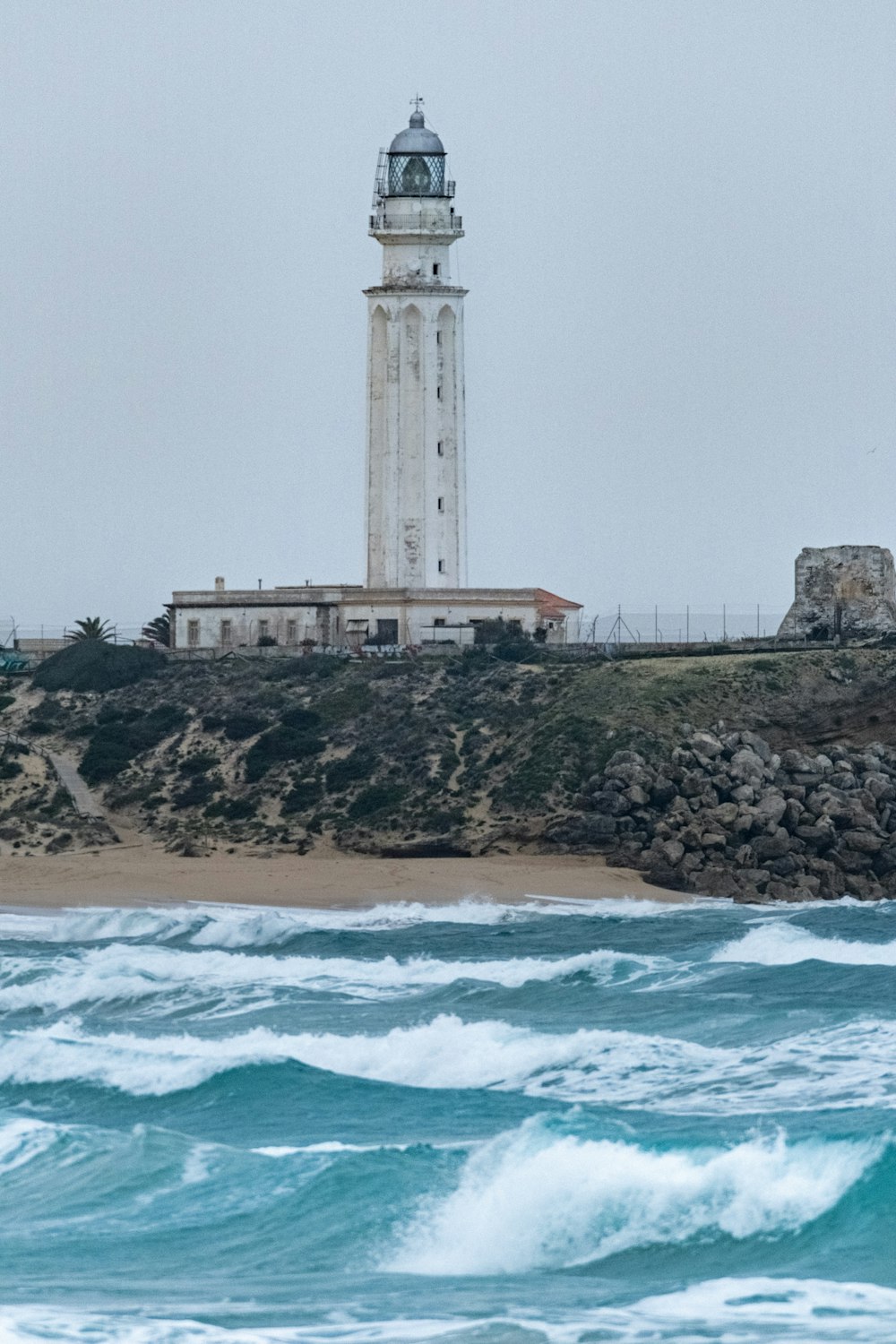 a lighthouse on top of a hill next to the ocean