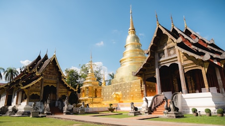 a row of gold and white pagodas in a park