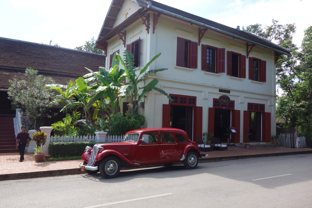 a red car parked in front of a white building