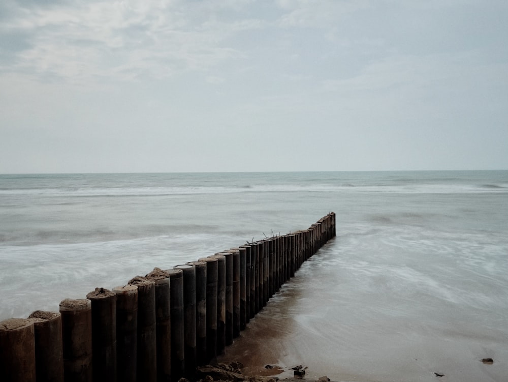 a long wooden fence sitting on top of a beach next to the ocean