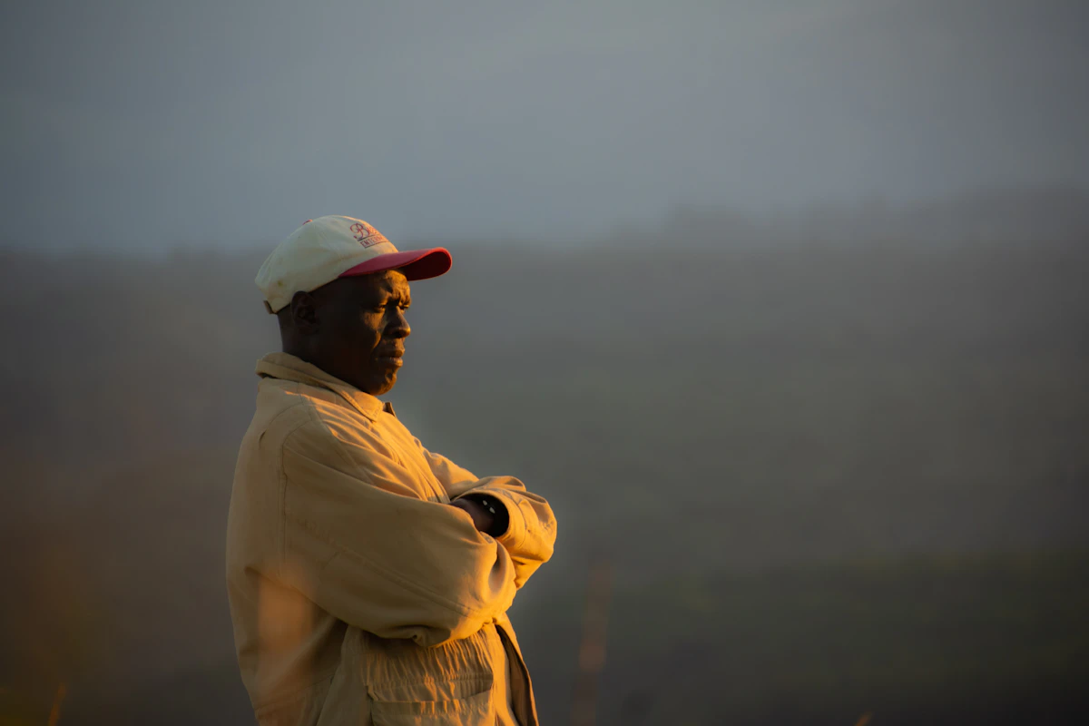 A guide standing on a hillside overlooking the Mara, coffee in hand