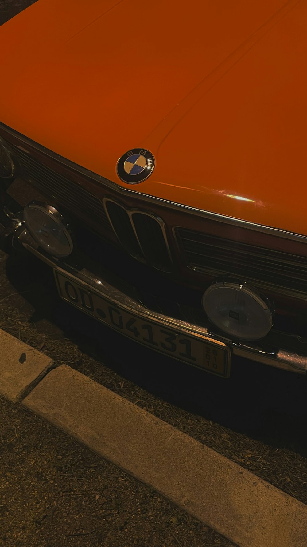 an orange bmw car parked on the side of the road